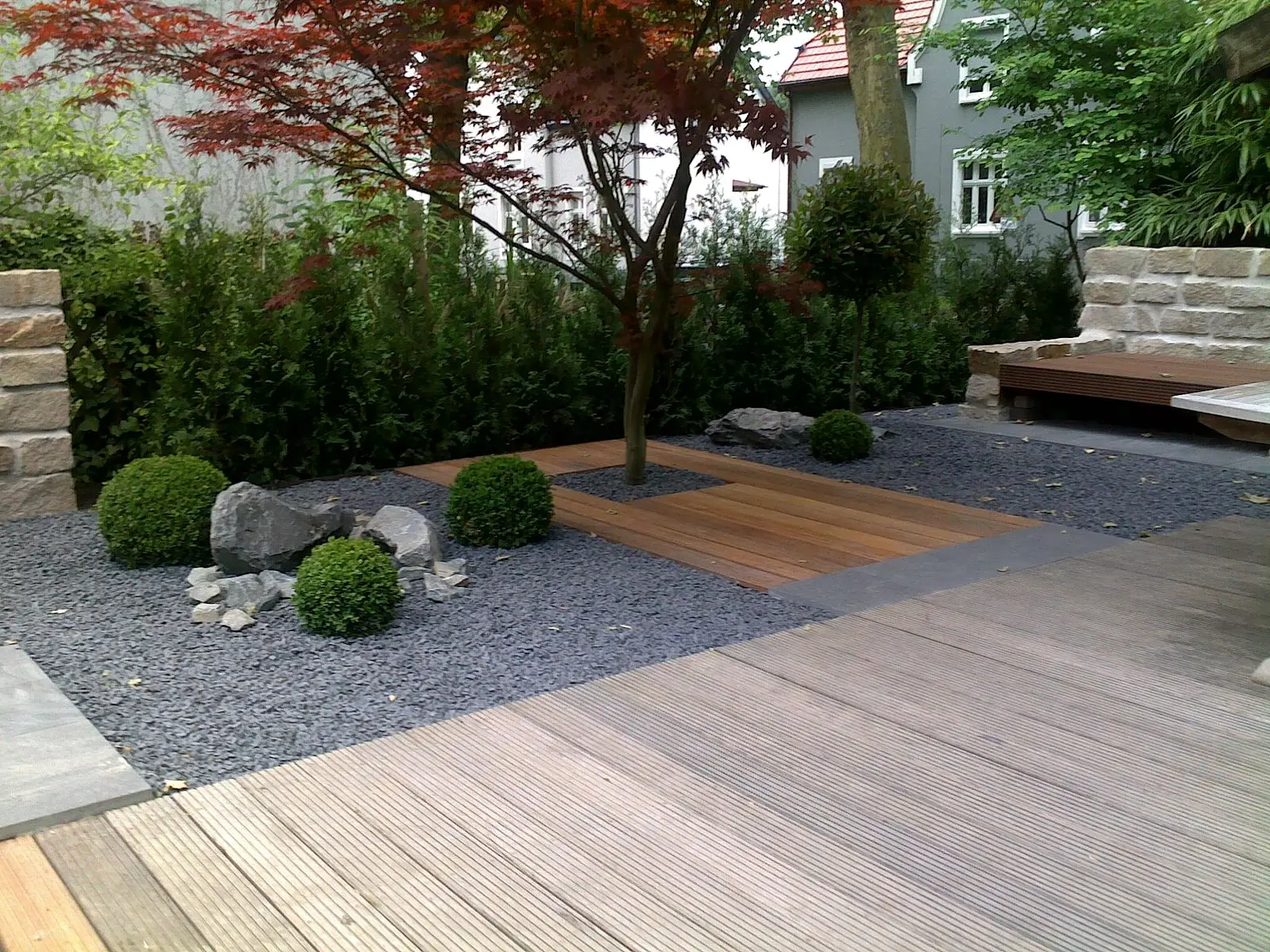 Holzstege und Kiesflächen in einem modern gestalteten Garten