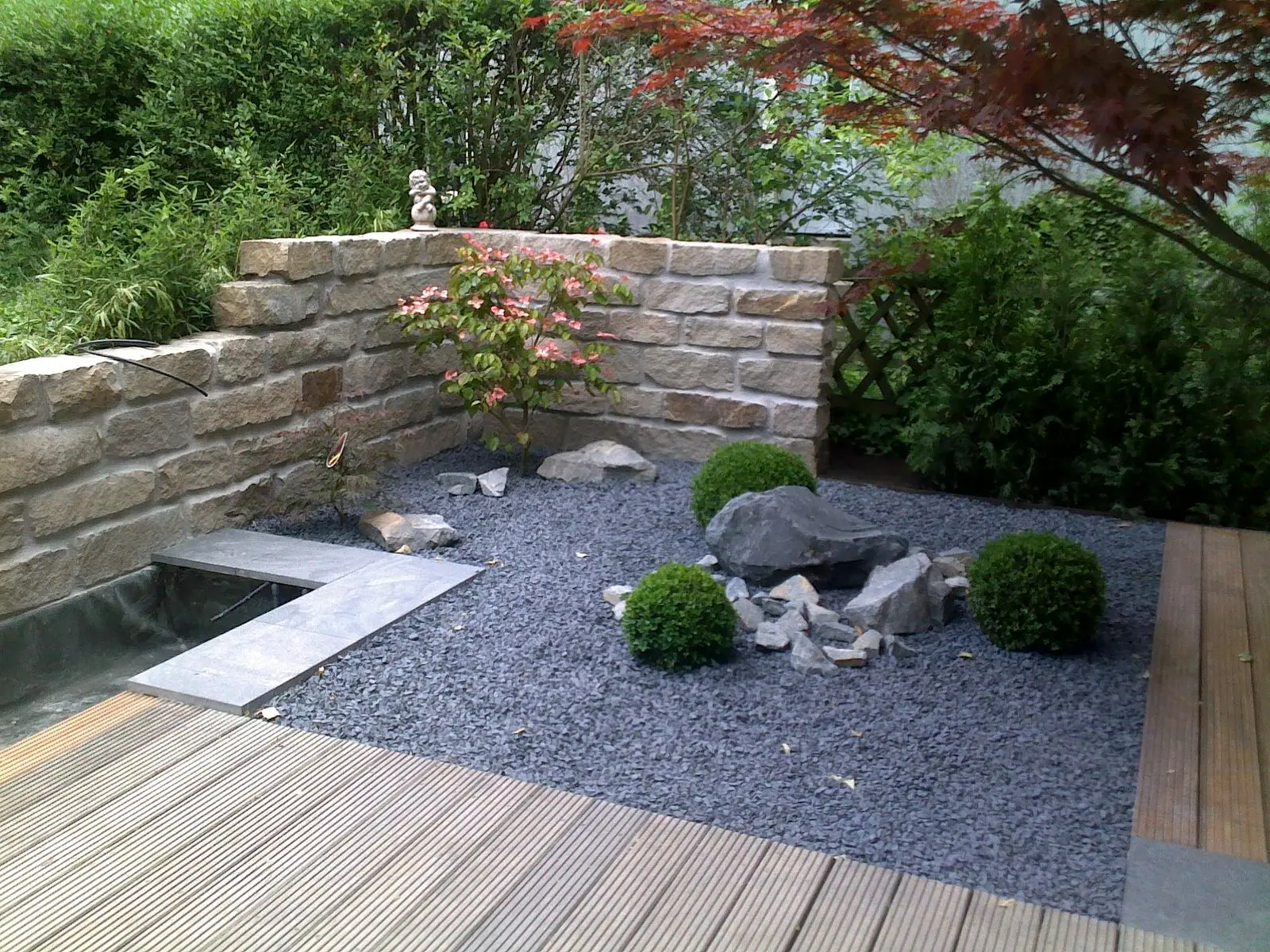 Gartenraum mit Natursteinplatten und Holzterrasse