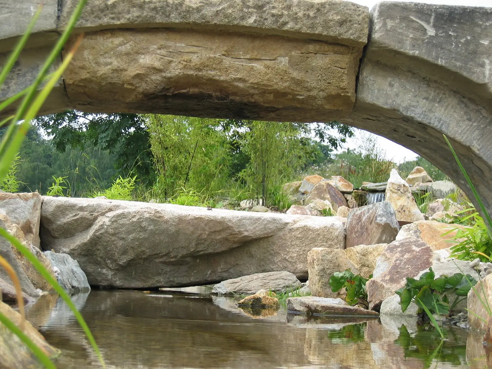 Massive Natursteinbrücke über einem Bachlauf