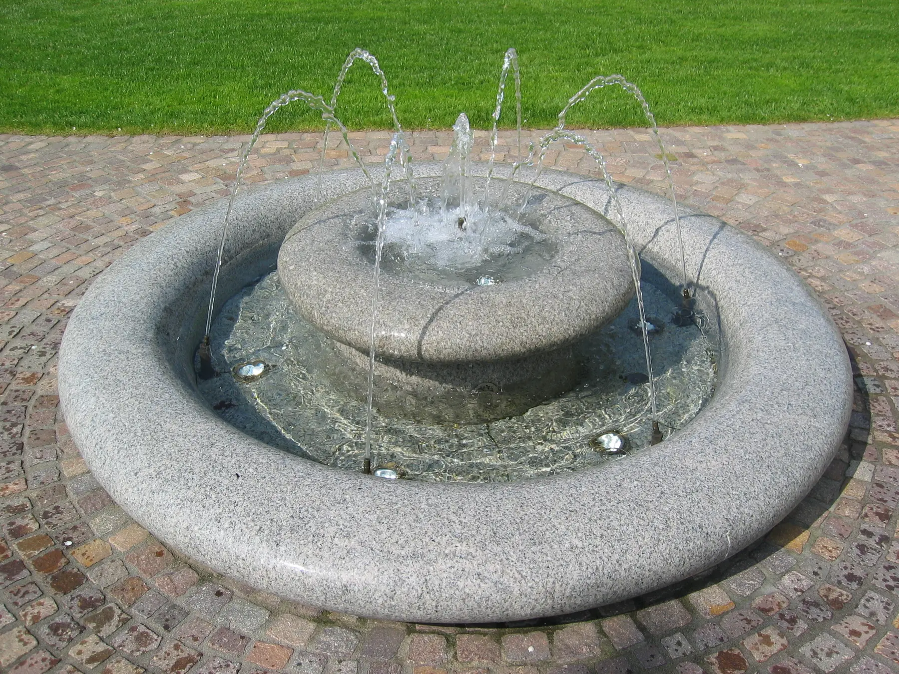 Runder Granitbrunnen mit fein geführten Wasserbögen