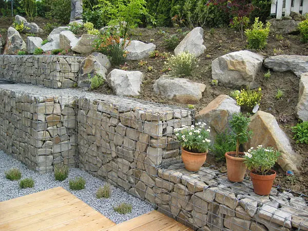 Terrassierte Gabionenwand mit Natursteinfüllung und Felsen