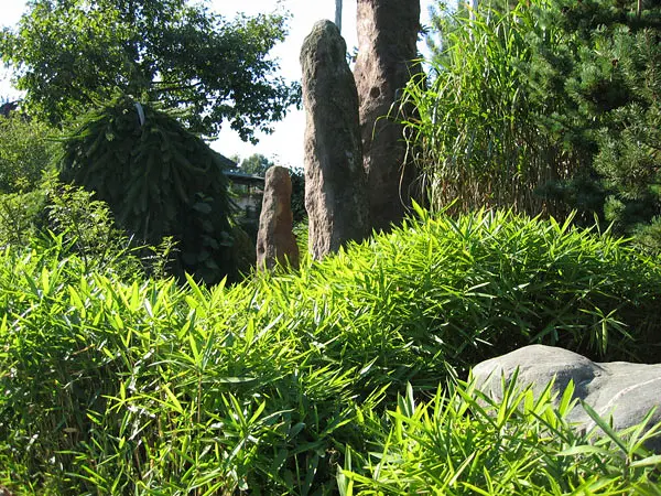 Hohe Naturstein-Monolithen zwischen Bambus und Gehölzen