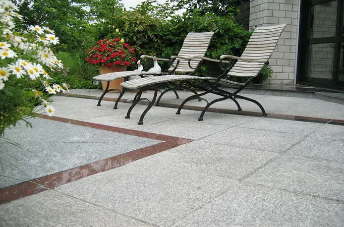 Terrasse aus großformatigen hellen Natursteinplatten mit roten Akzentbändern