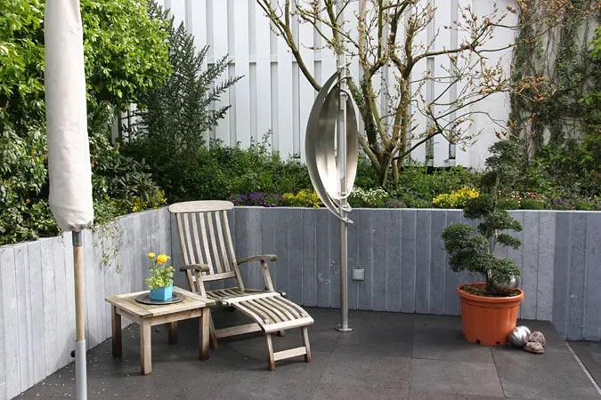 Terrasse mit dunklen Natursteinplatten und vertikaler Naturstein-Wandbekleidung